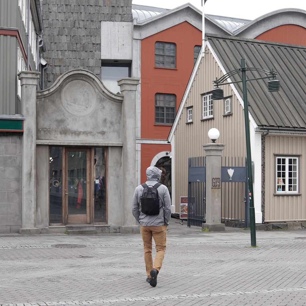 person walking in rainy European town wearing a black backpack