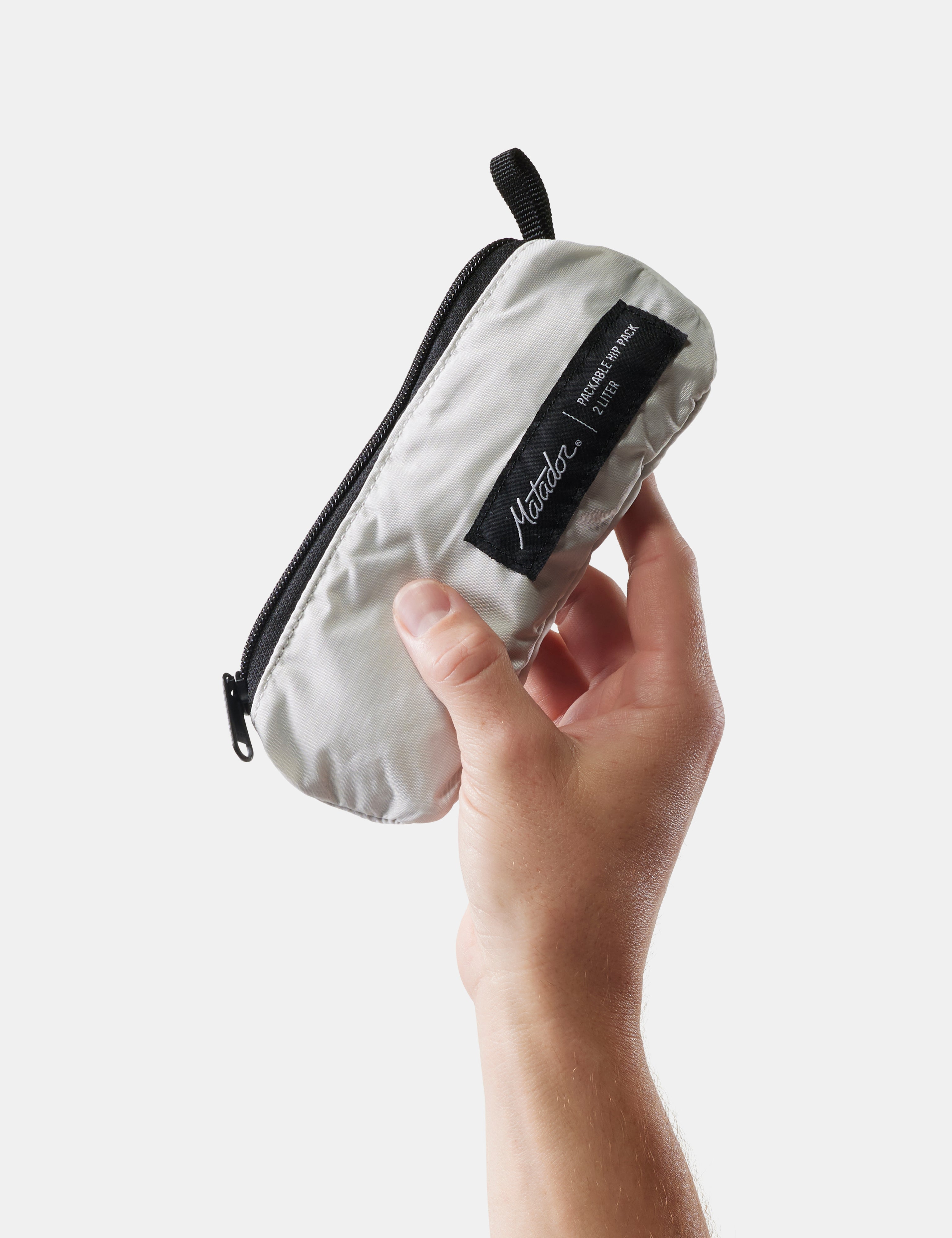 Hand holding a white hip pack pouch against a light gray background