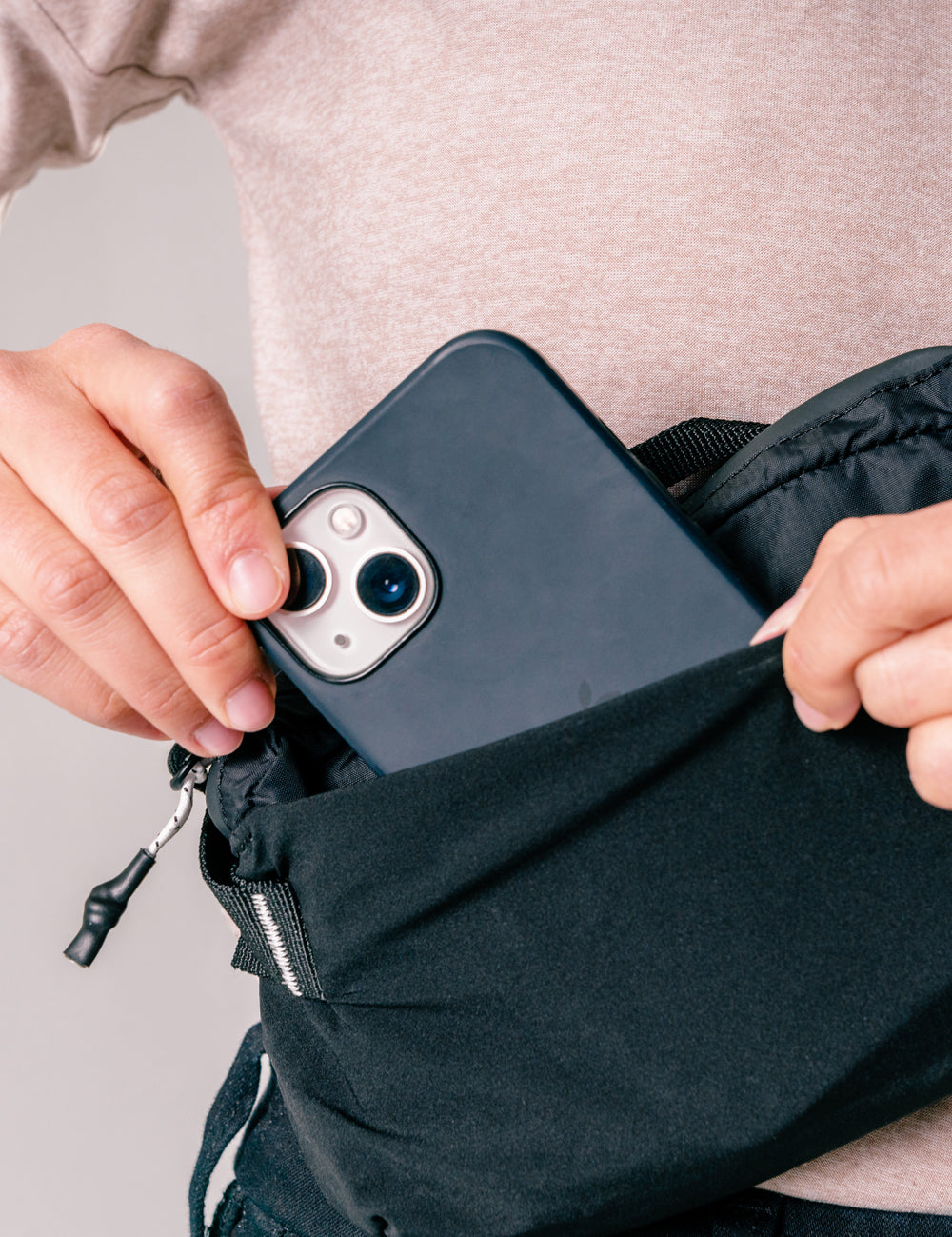 hand pulling phone out of black sling