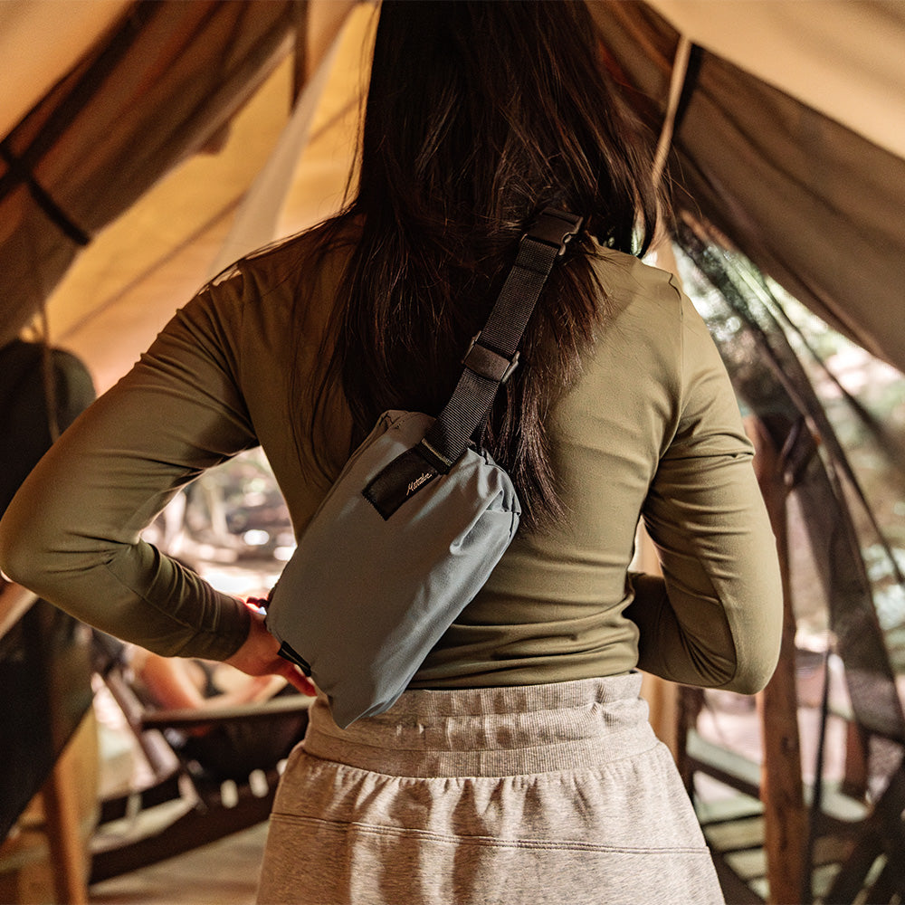 woman walking into glamping tent with slate crossbody sling