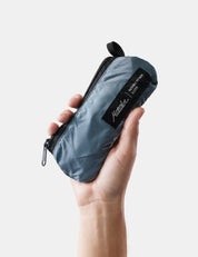 Hand holding a blue compact pack with a brand label on a light background