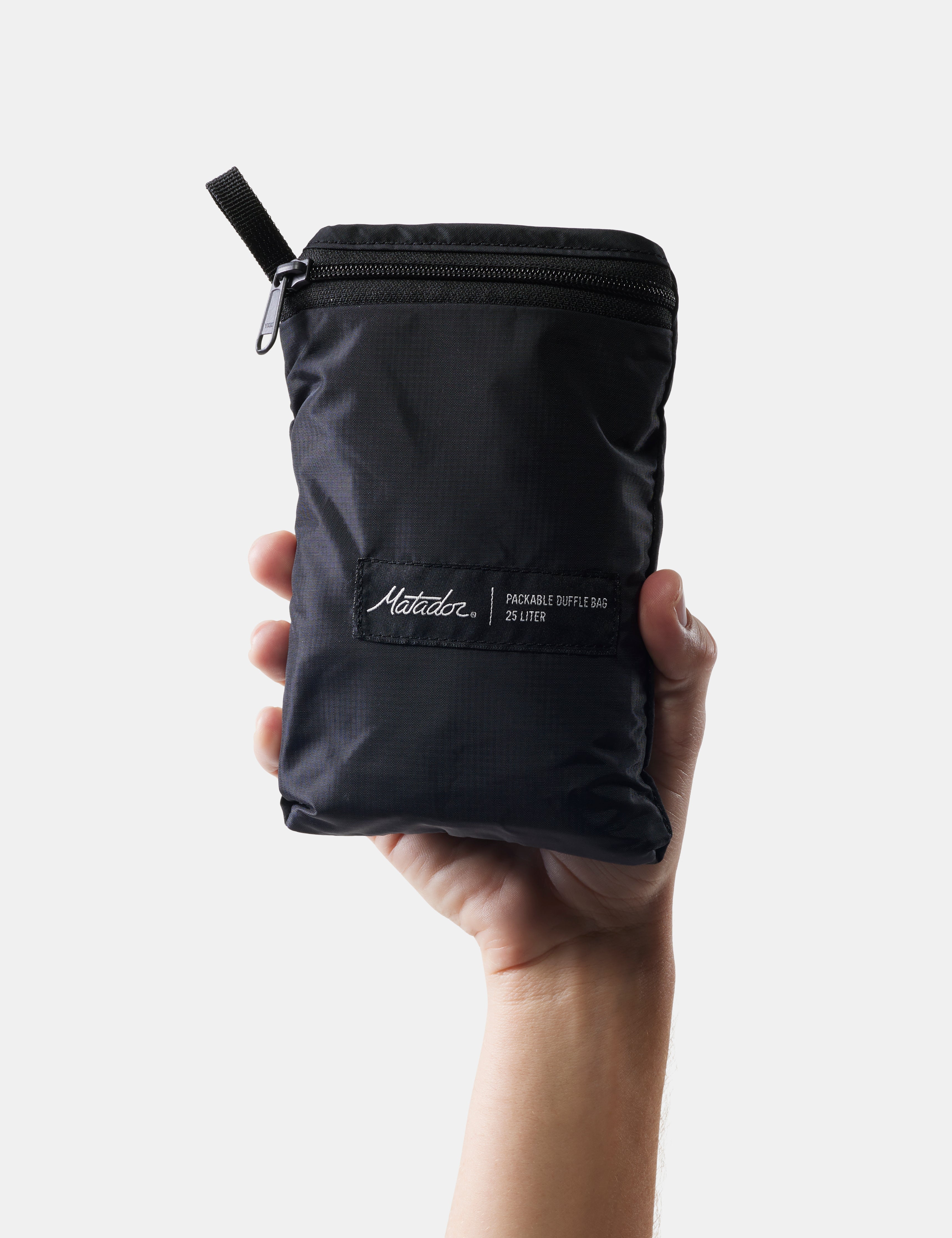 Black zippered pouch held by a hand on a white background