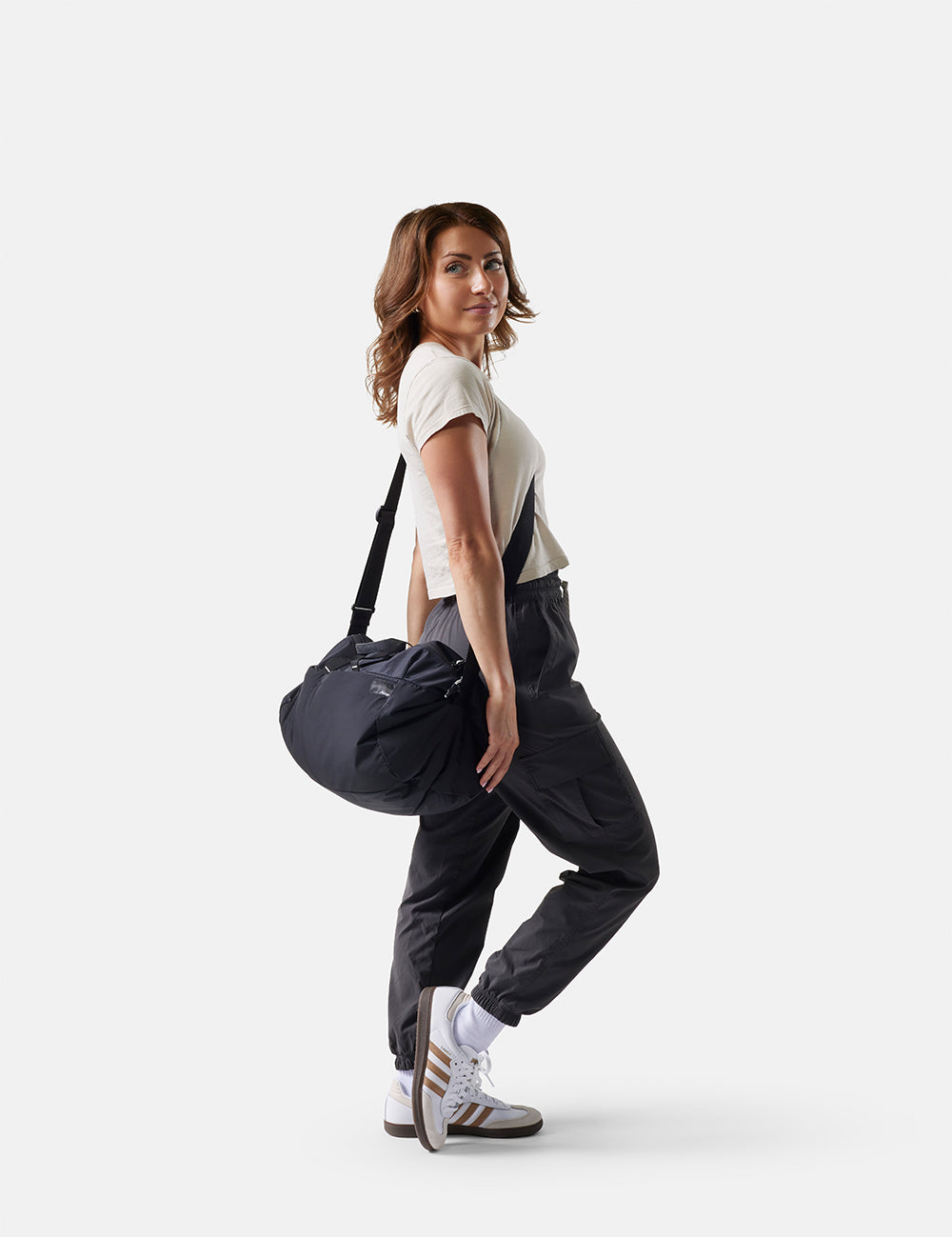 Woman holding a black duffel bag on a white background