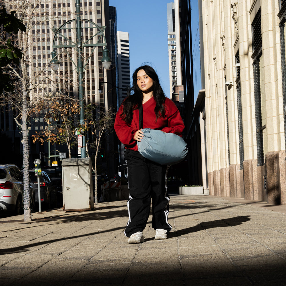 woman in red with blue duffle on city sidewalk