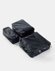Three black packing cubes stacked on a white background