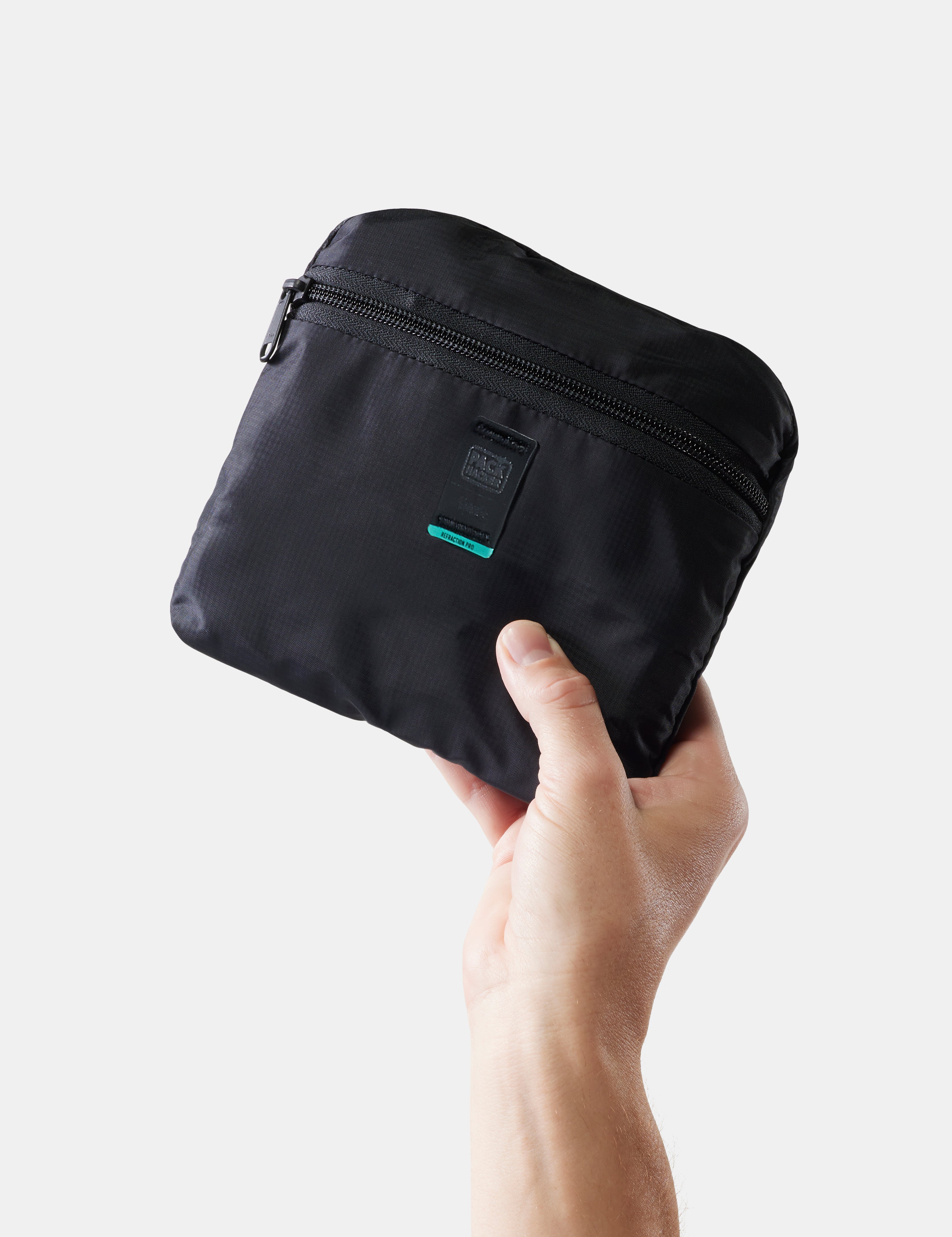 Black pouch held by a hand on a light gray background
