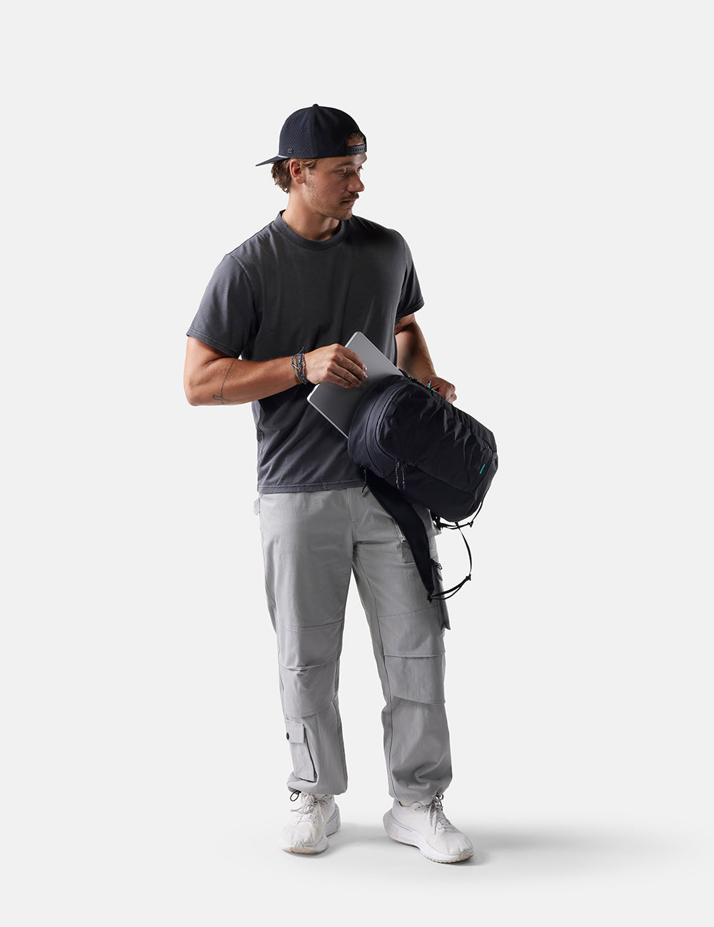 Man holding a black backpack against a white background