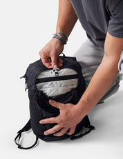 Person opening a black backpack on a white background
