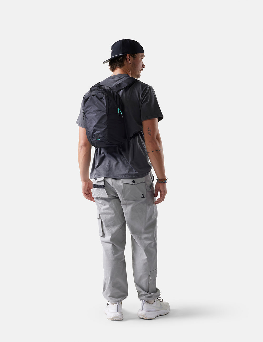 Person wearing a black backpack and gray pants on a white background