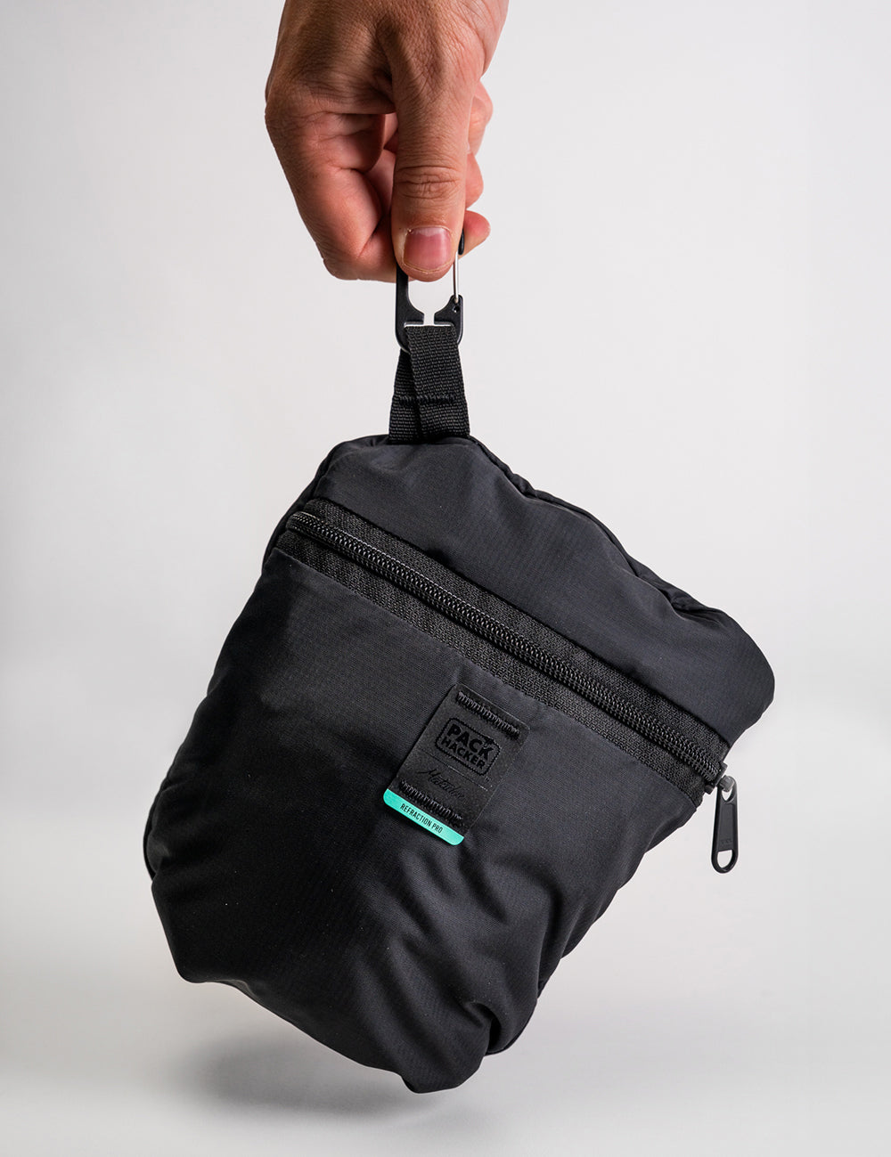 hand holding packed up backpack by carabiner