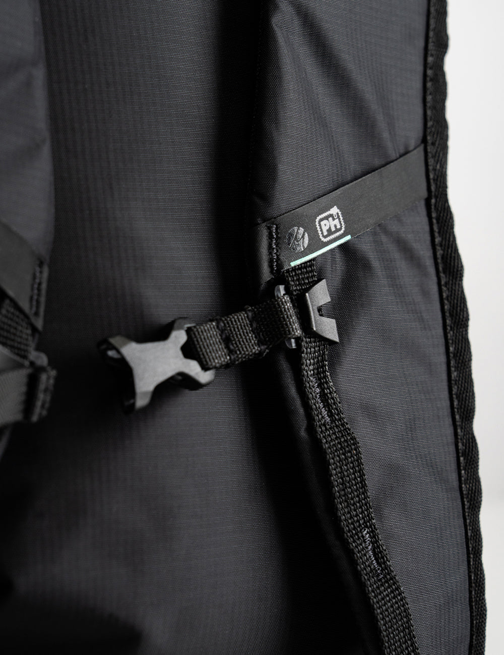 detail view of black backpack strap with Matador M logo and Pack hacker pH logo