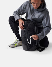 Person in gray jacket and black pants with a black backpack on a white background