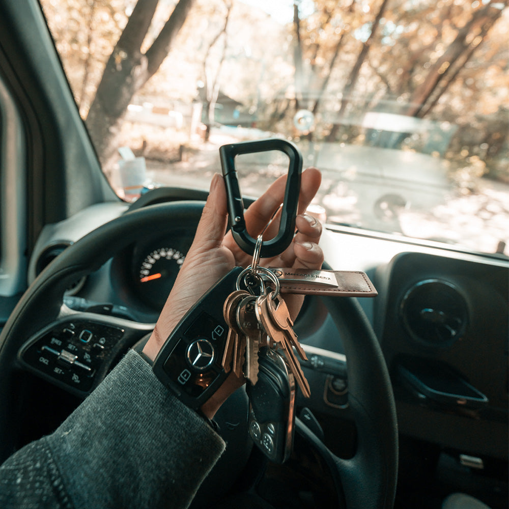 hand holding black carabiner in drivers seat of car