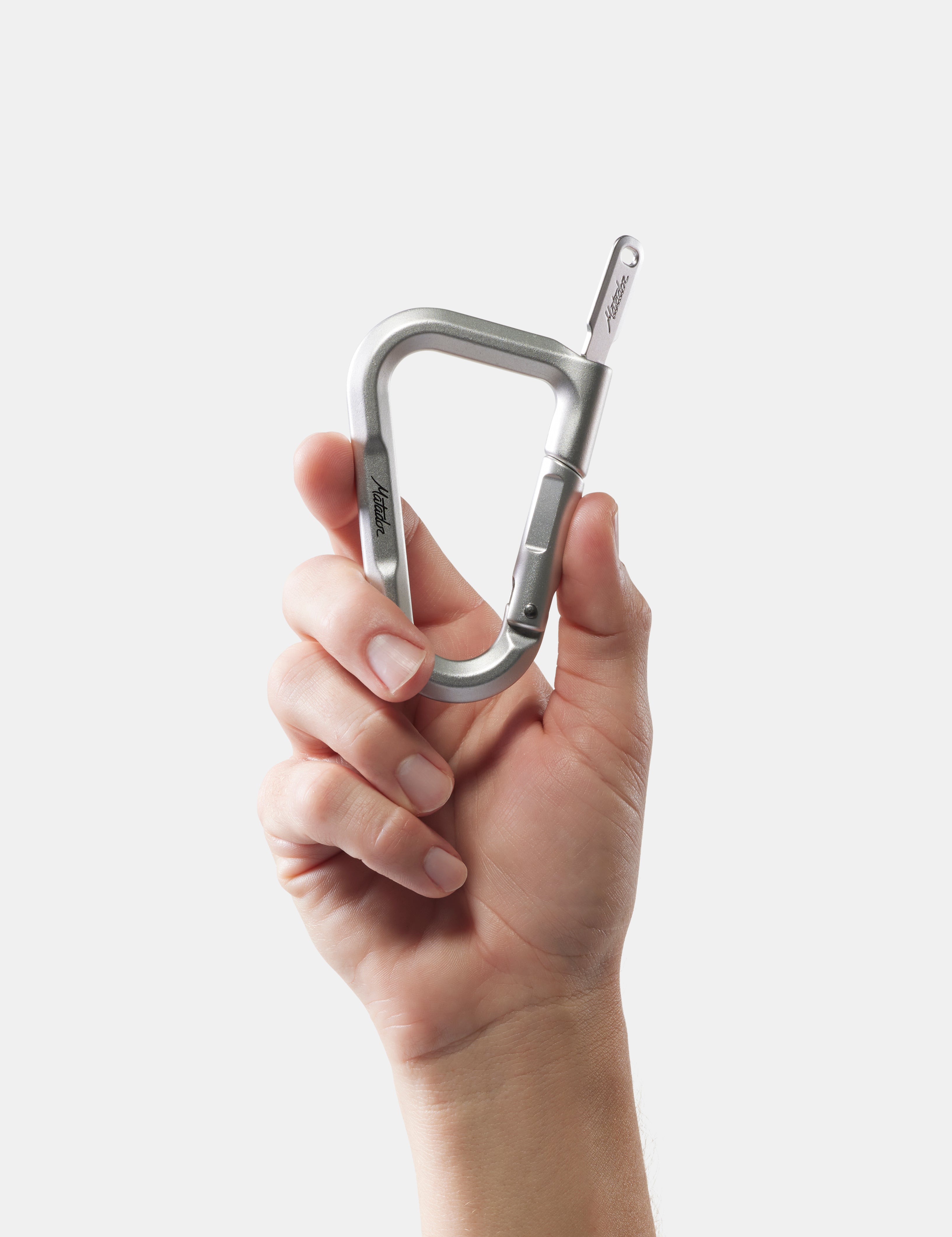 Hand holding a silver carabiner against a white background