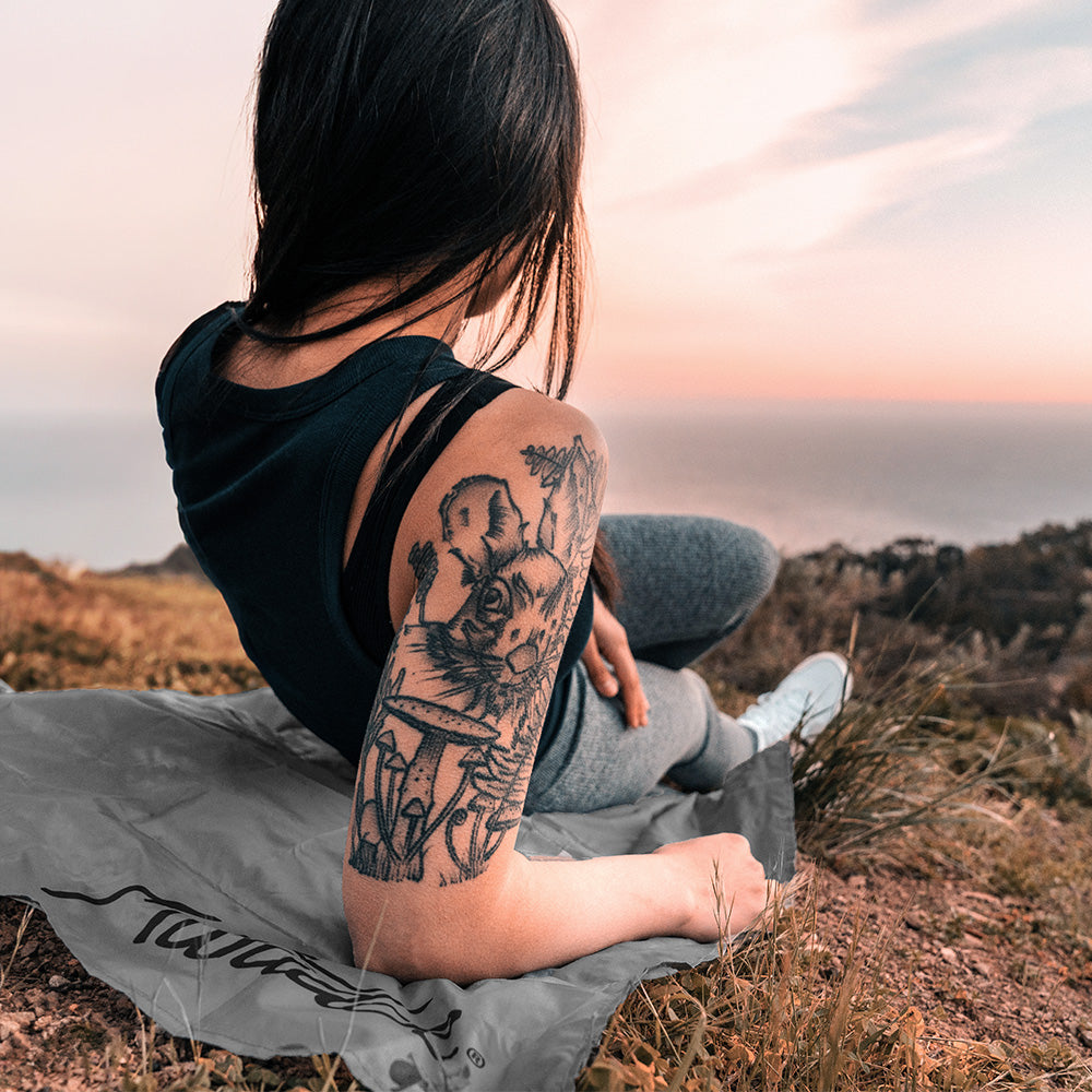 Woman on coastline, laying on pocket blanket