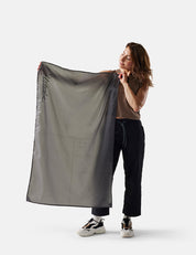 Person holding a large gray fabric with a brand logo on a white background