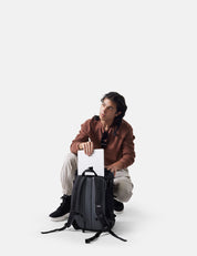 Person sitting with a backpack on a white background