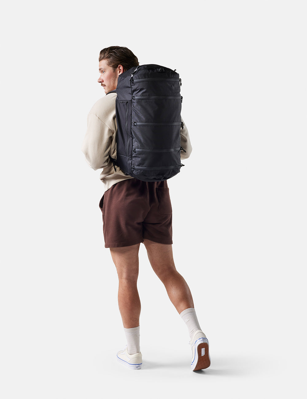 Person wearing a large black backpack on a white background