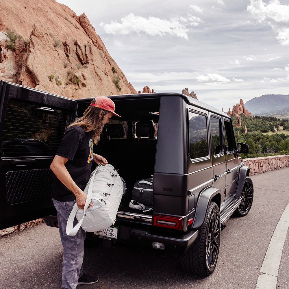 man putting white bag in back of vehicle