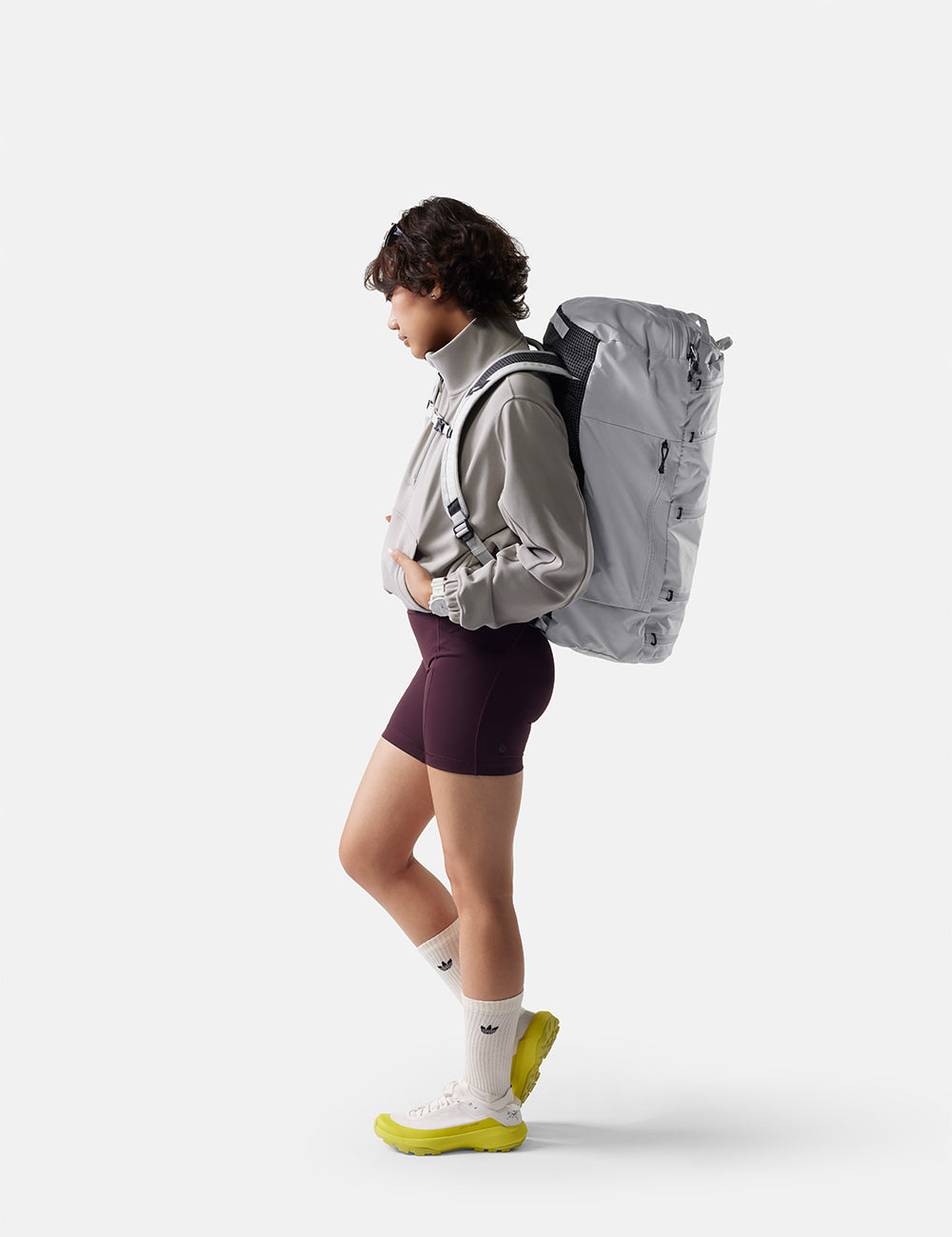 Person wearing a gray backpack and purple shorts on a white background