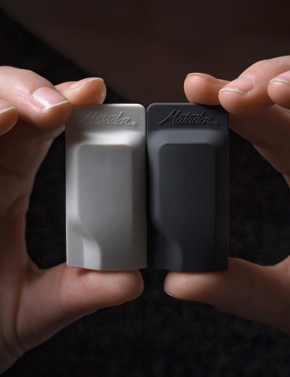 hand holding light gray and black toothbrush caps side by side