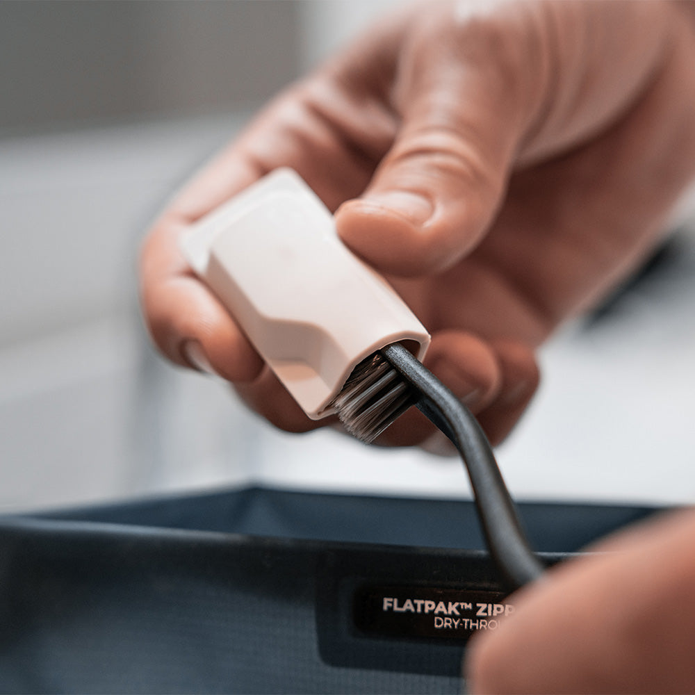 hand pulling white toothbrush cap off of black toothbrush