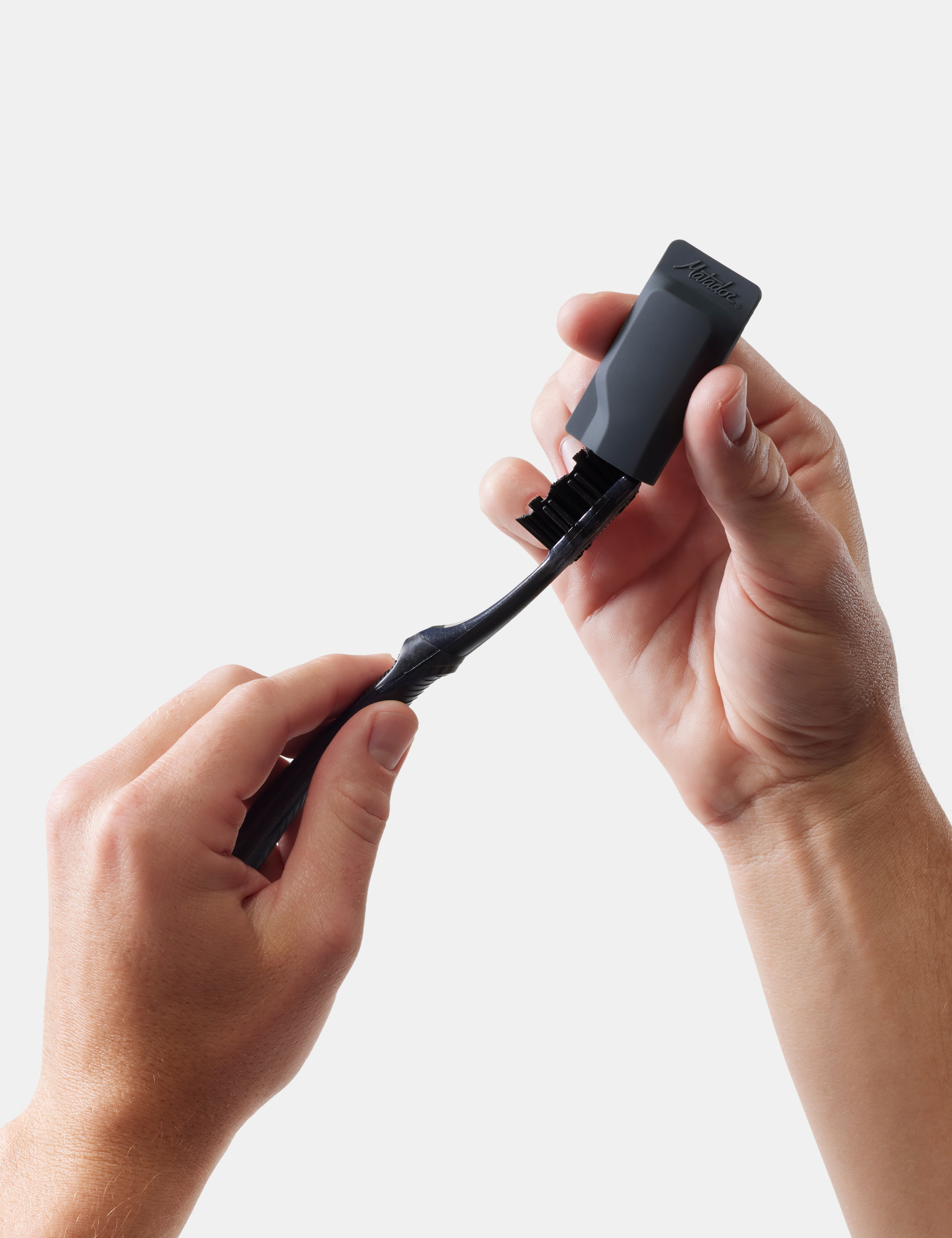 Person holding a black toothbrush and cap on a white background