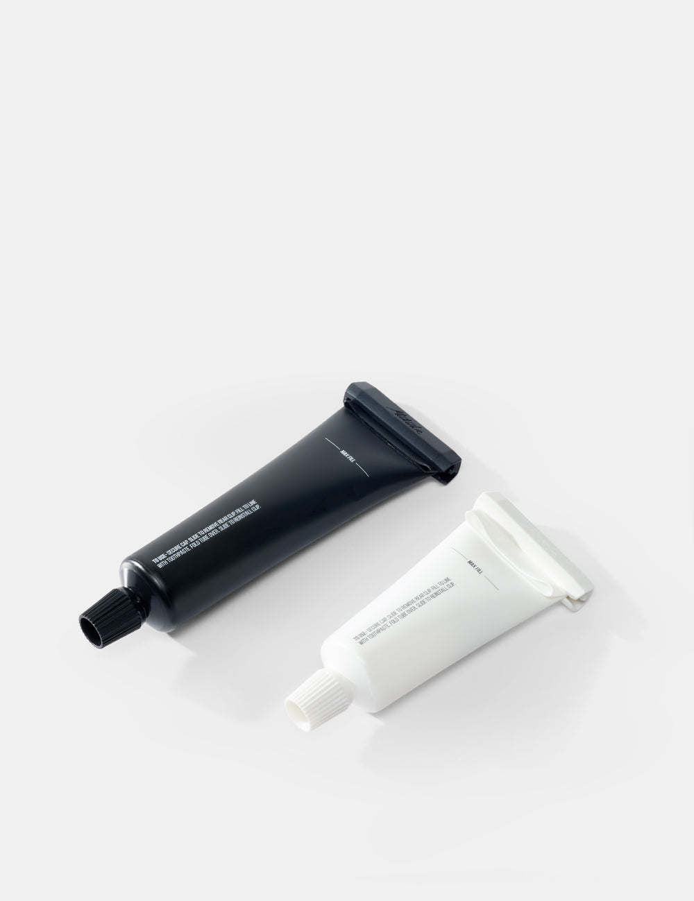 Two tubes , one black and one white, on a light gray background