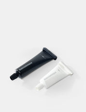 Two tubes , one black and one white, on a light gray background