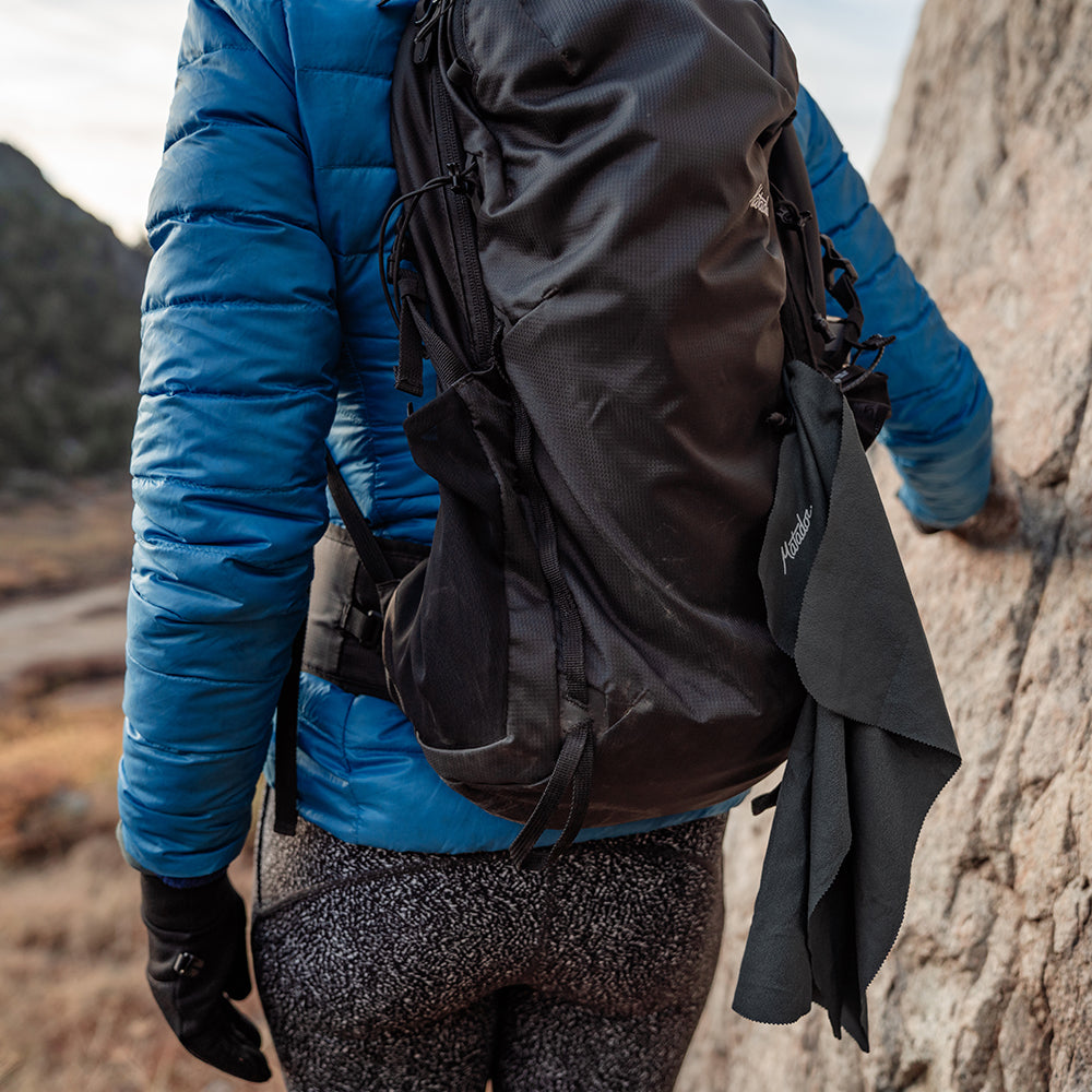 person on hiking trail with small towel attached to the outside of their backpack
