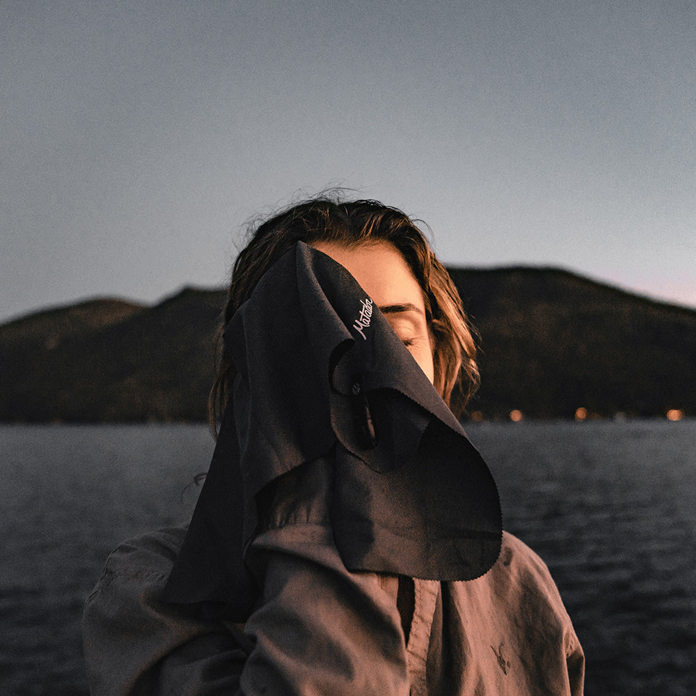 woman at twilight alpine lake, drying face with small towel