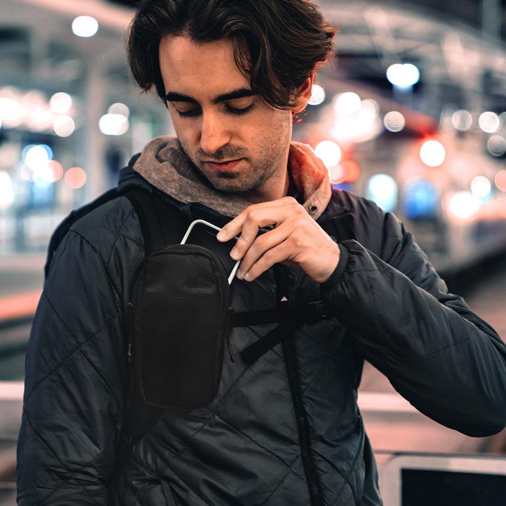 man at city train station pulling phone out of black speed stash