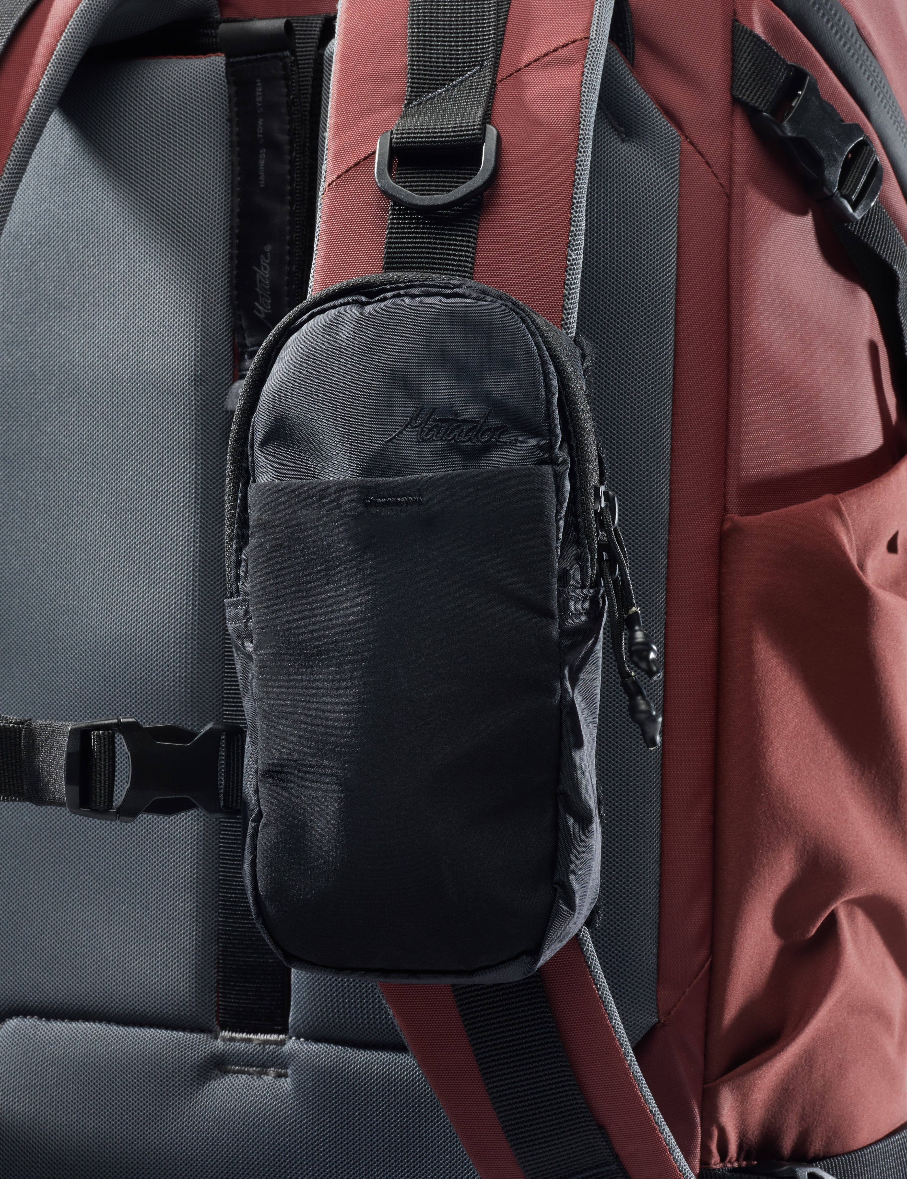 Black pouch attached to a red and gray backpack