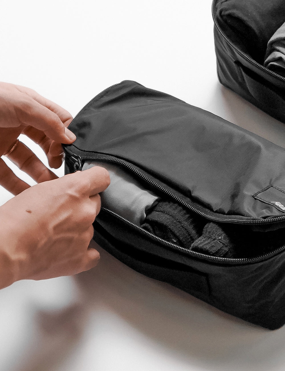 hands zipping up small packing cube