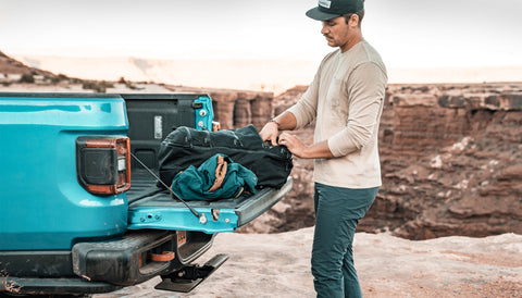 Man packing SEG45 in truck bed at the edge of a desert canyon