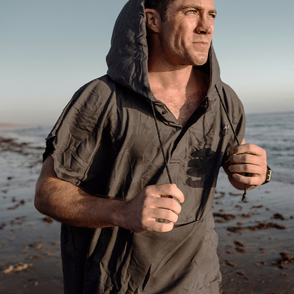 Man on beach, wearing gray poncho