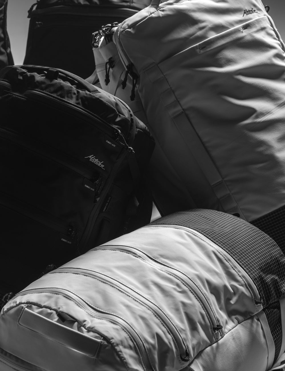 pile of white and black backpacks lit with moody shadows