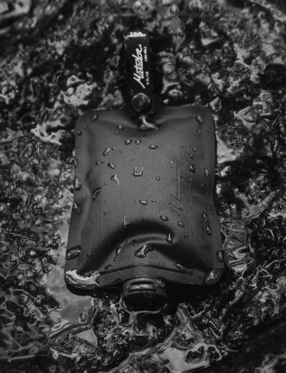 Black flatpak toiletry bottle laying in water