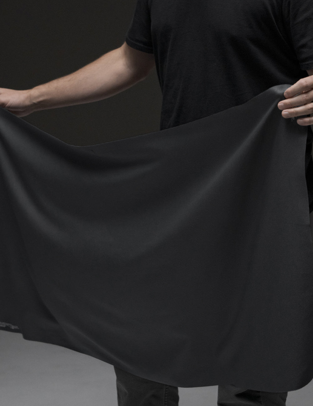 person in dark studio holding out towel