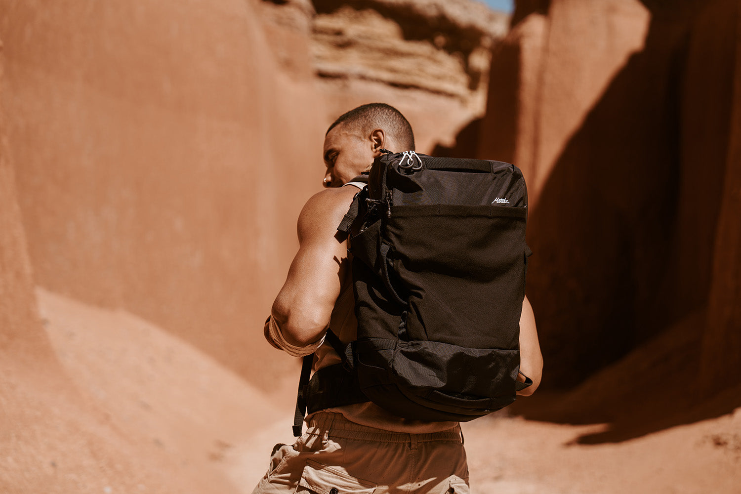 Person with a large black backpack walking through a desert canyon.