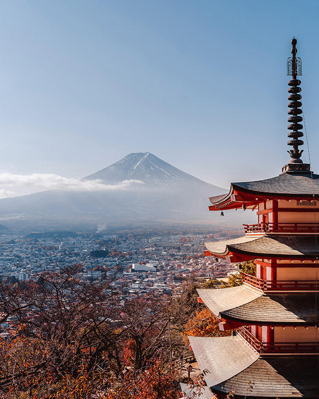 Red pagoda overlooking Mount Fuji in Japan with fall leaves.