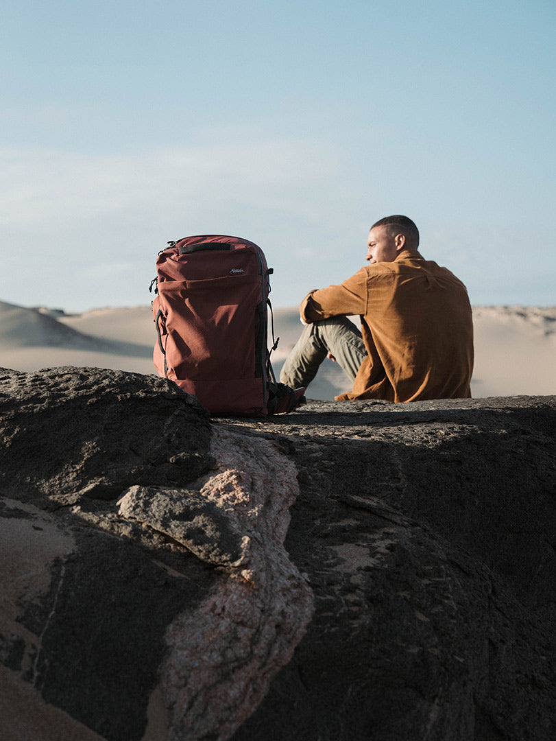 someone sitting on the sand dune with a backpack