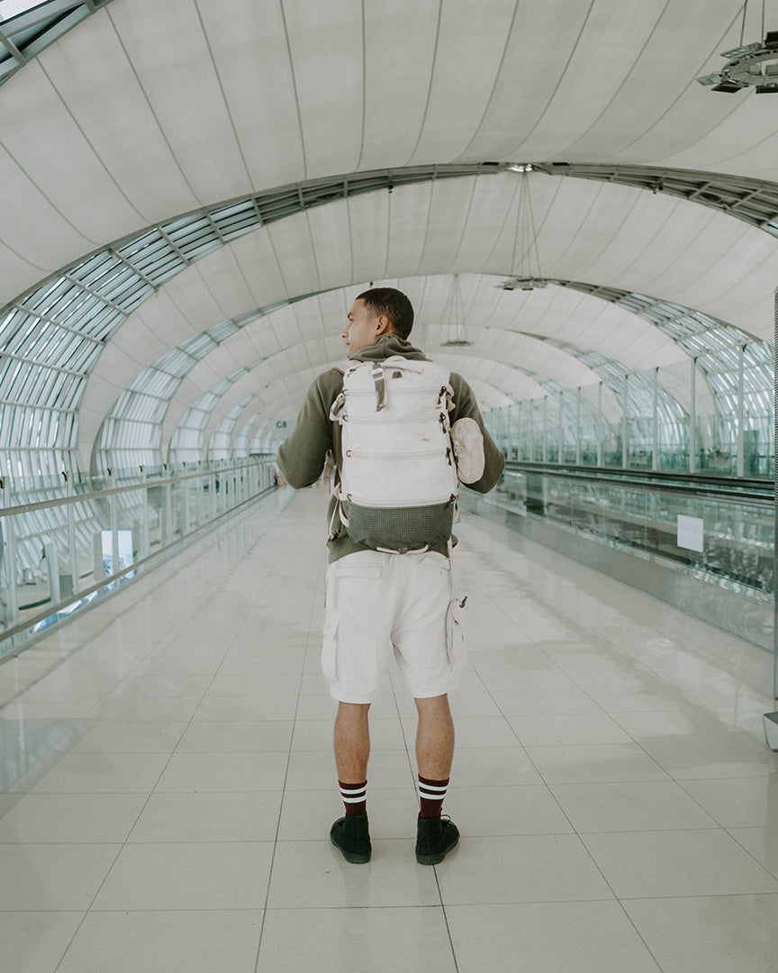 person wearing a travel backpack at an airport terminal during summer