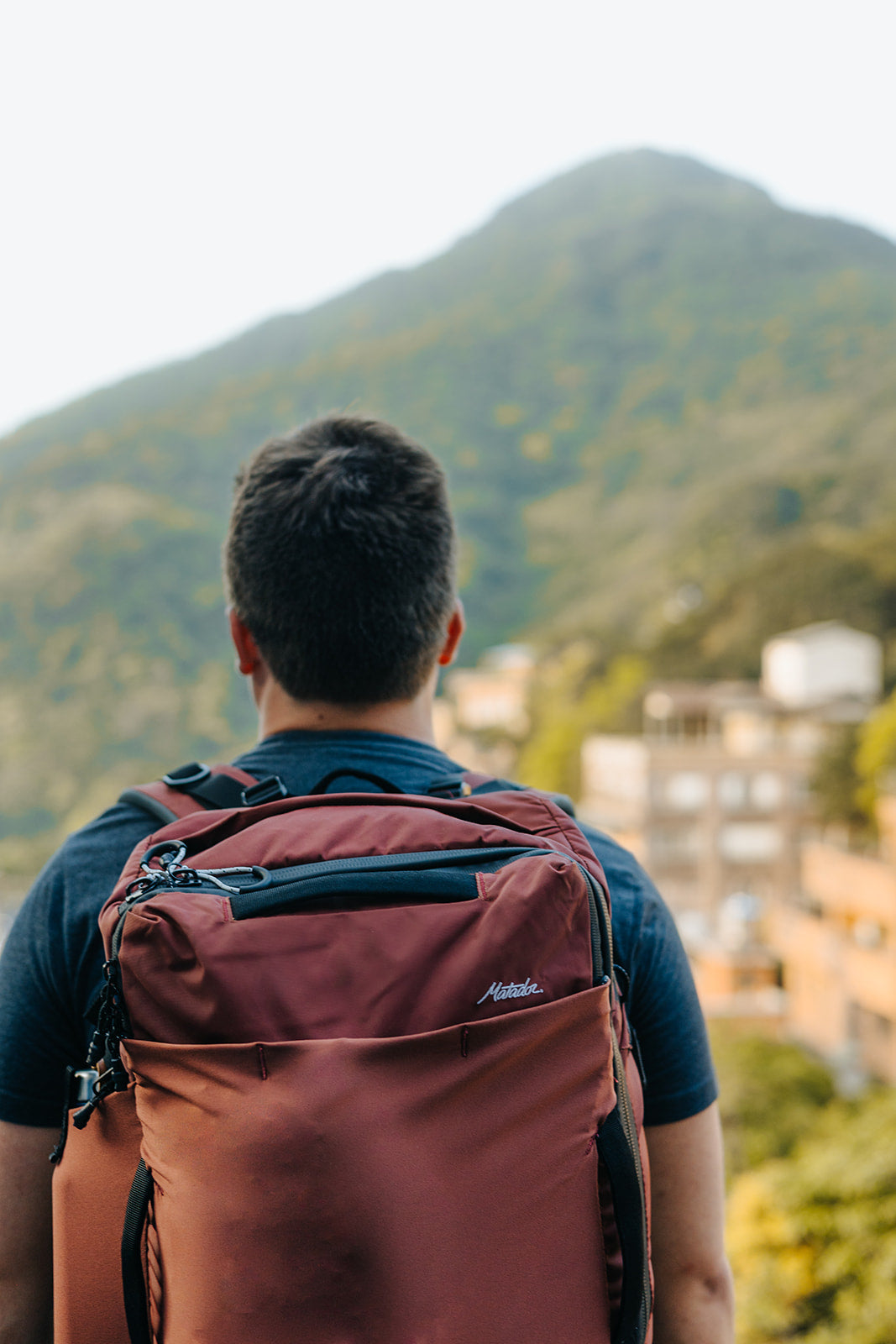Man looking at a mountain view while wearing a backpack