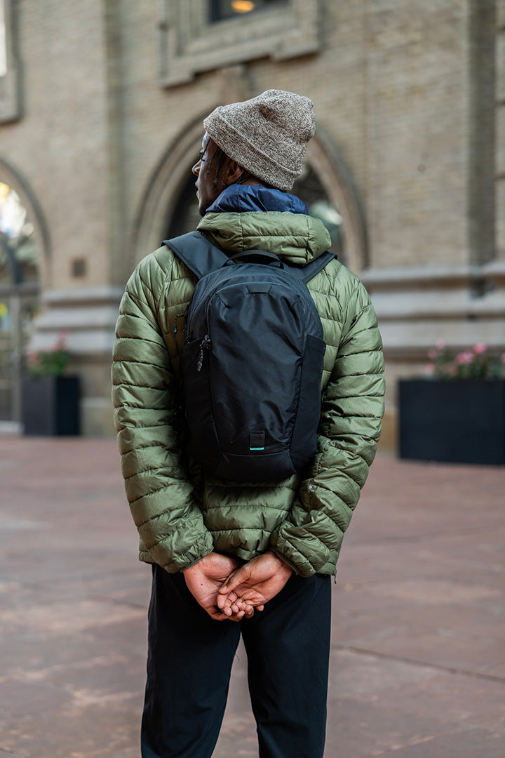 man with a green jacket wearing a black backpack standing outside