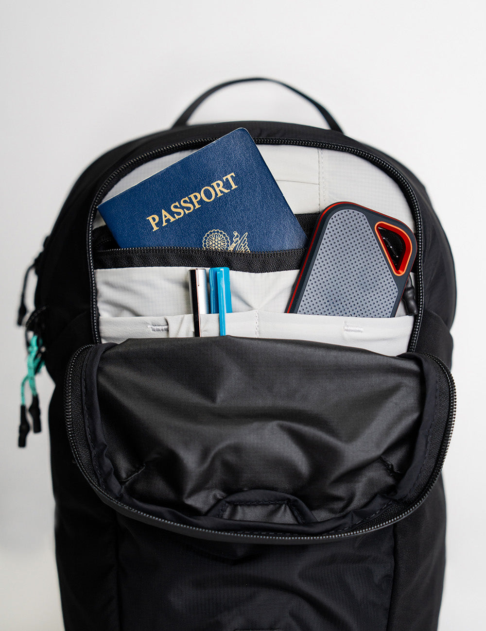 Backpack unzipped to show organized passport, pens and power bank
