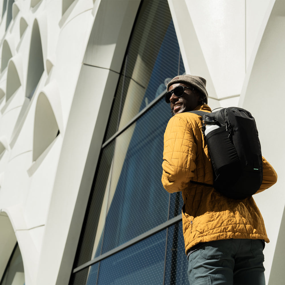 Man in city wearing yellow jacket, wearing black backpack