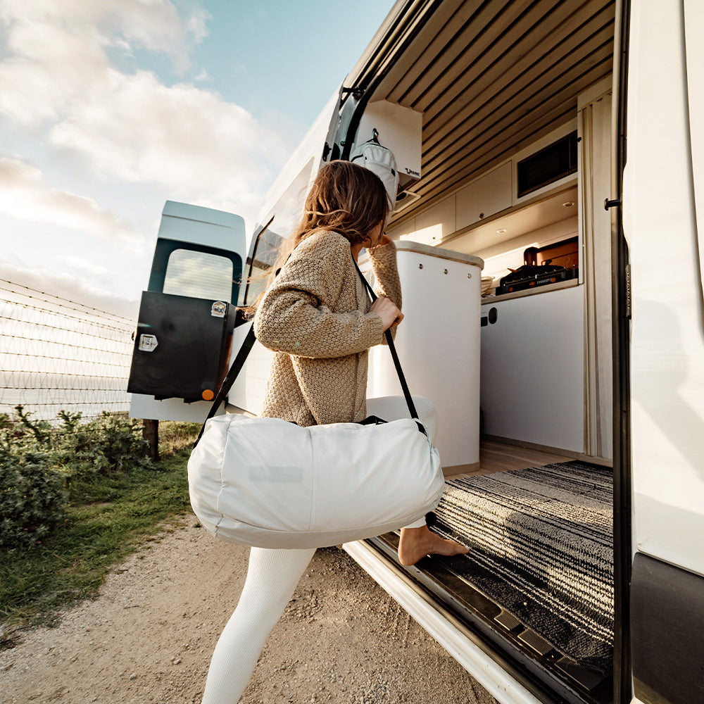 woman stepping into travel van with white duffle