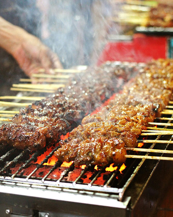 meat skewers on the grill at a street food stall