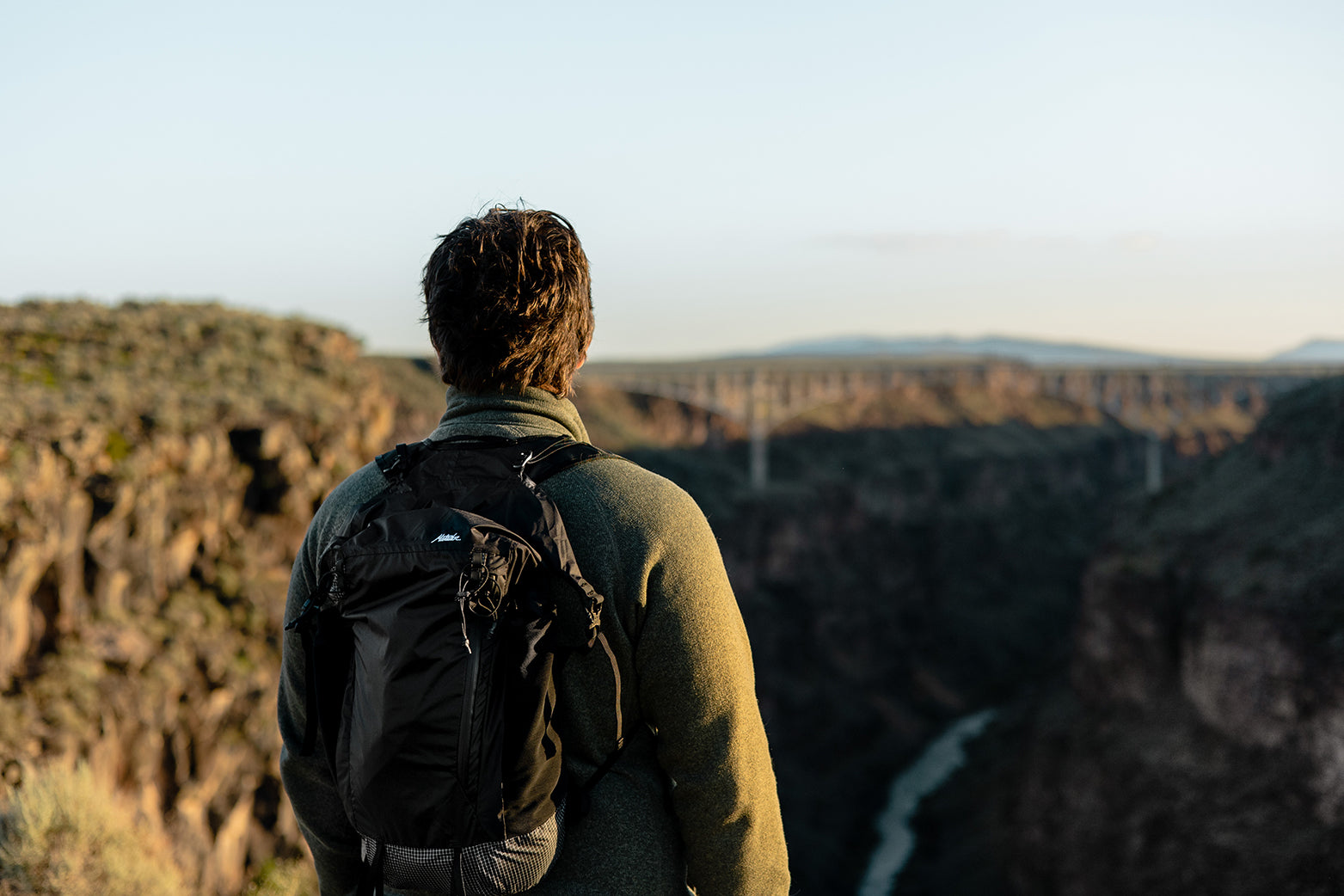 man wearing backpack looking at a view